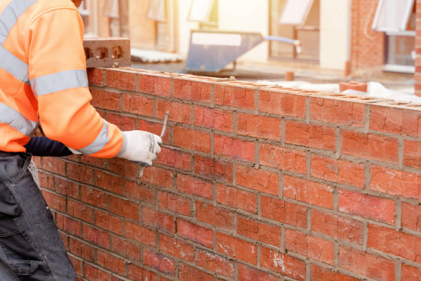 Bricklayer laying bricks on mortar on new residential house construction